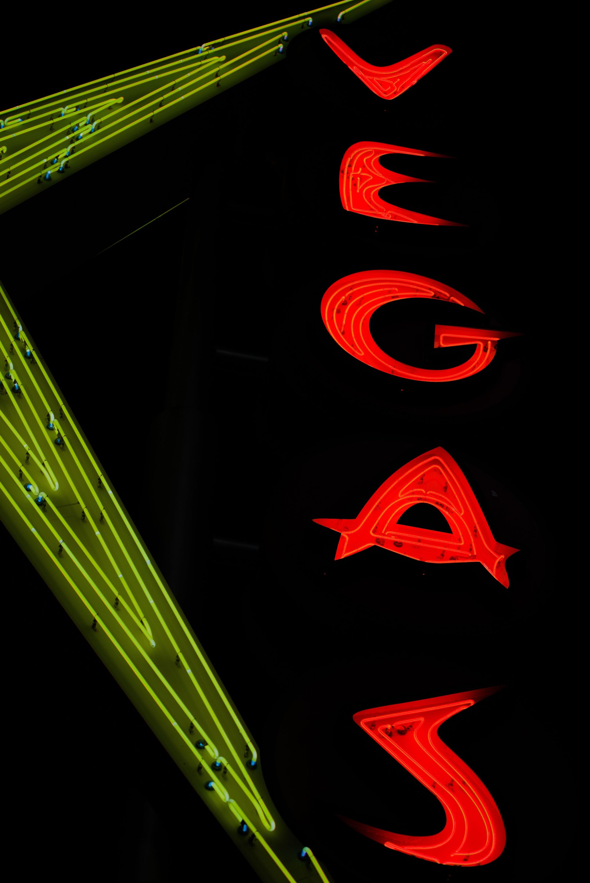 Vertical red neon letters spelling Vegas beside glowing green tubes